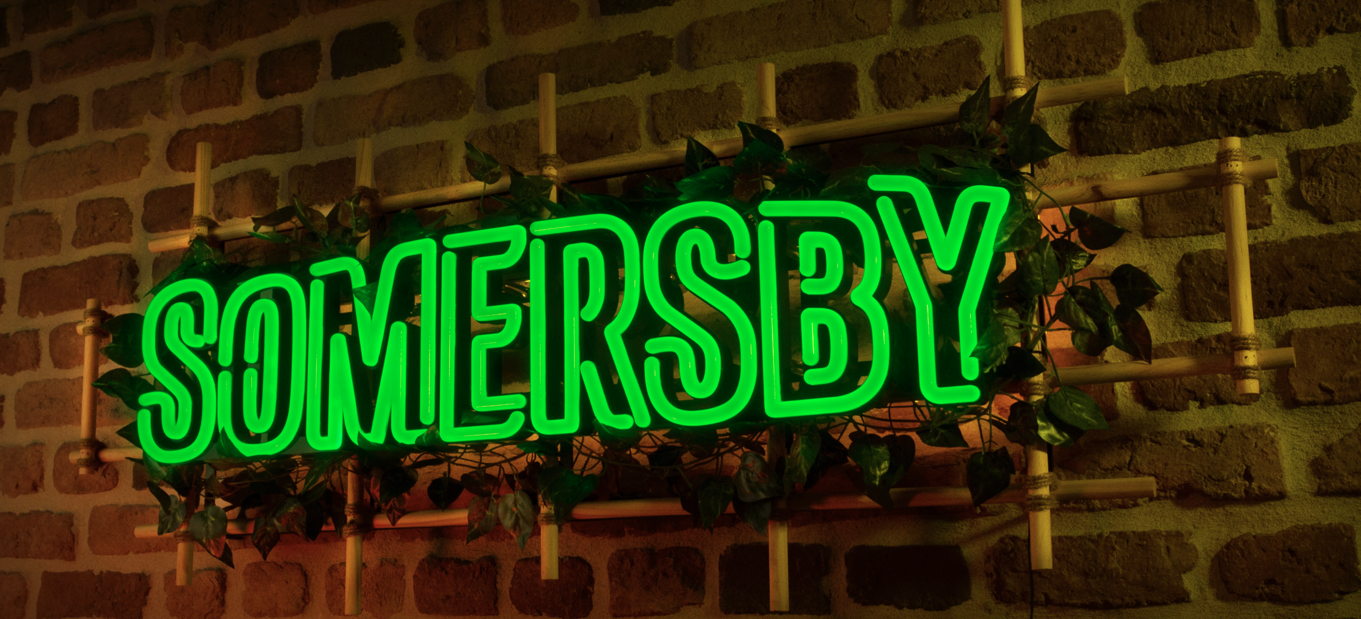 Green LED neon sign of somersby on brick wall